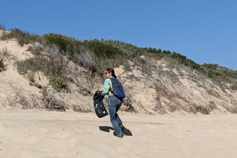 woman looking for trash on the beach