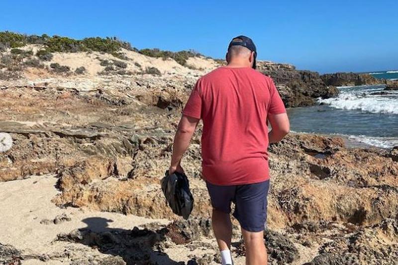 man looking for trash on rocks