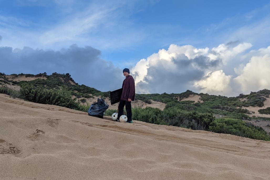 Rinaldo on sand dune with bag of trash